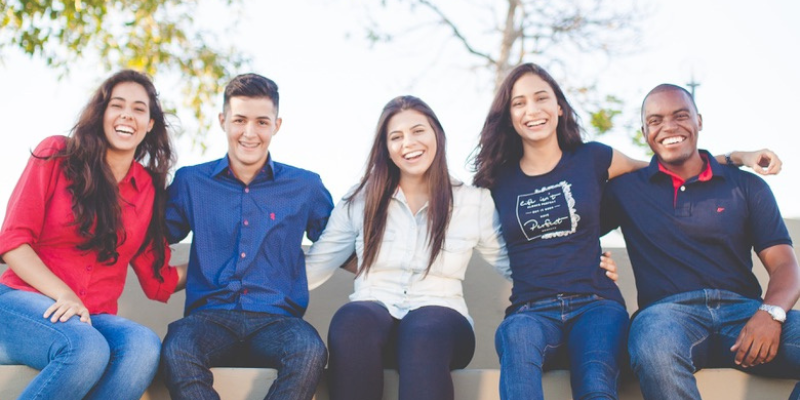 five young adults sitting outdoors on a ledge