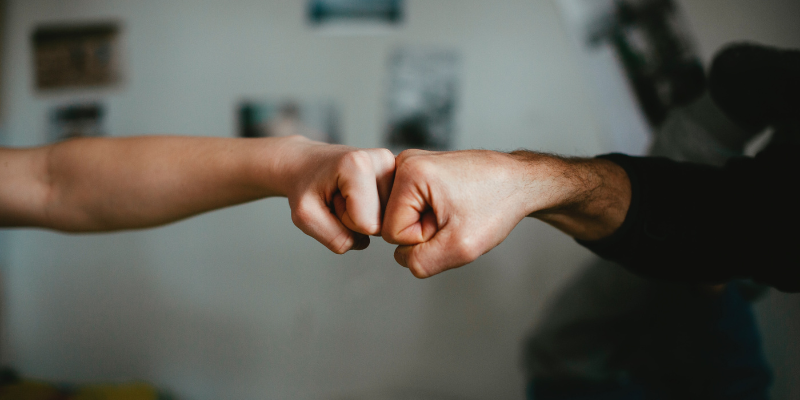 two hands fist bump each other in encouragement