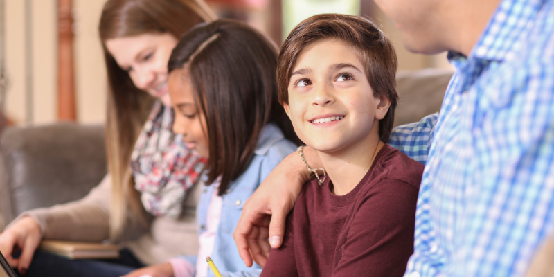 boy sits on couch and looks up at adult caregiver