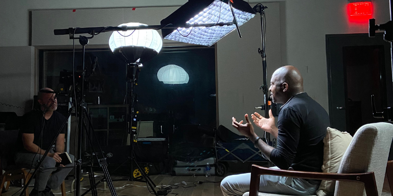 man being interviewed for a video with lights and cameras