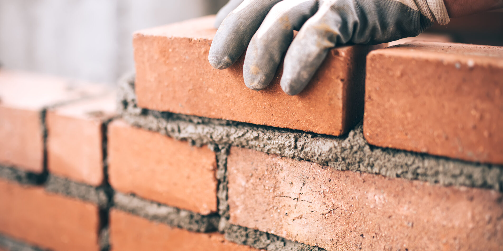 Close up of industrial bricklayer installing bricks on construction site