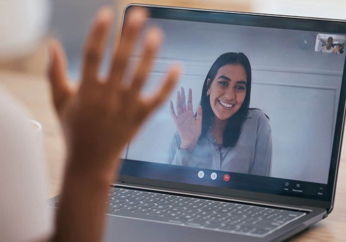 Smiling lady waving on the computer to someone