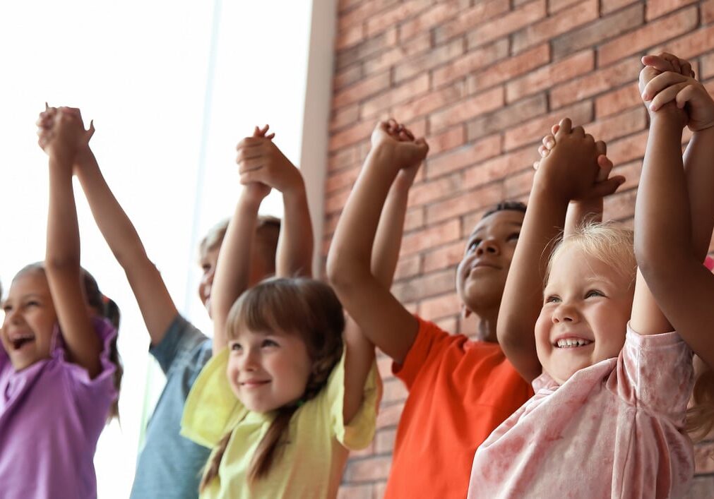 Little children holding hands together indoors. Unity concept